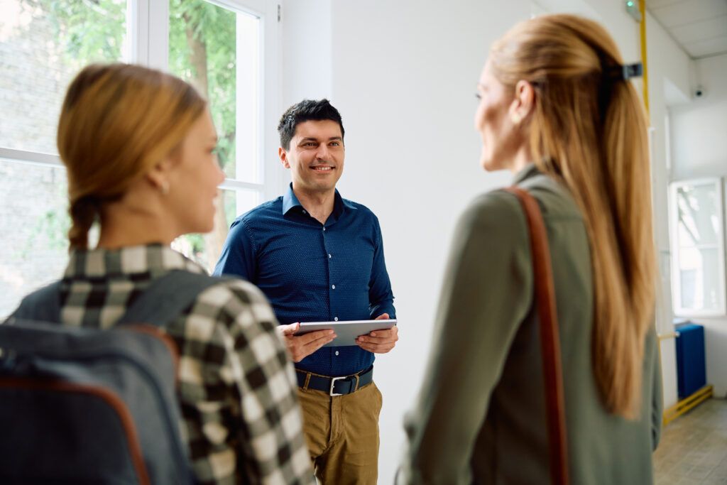 Teacher talking to mother and daughter in school hallway