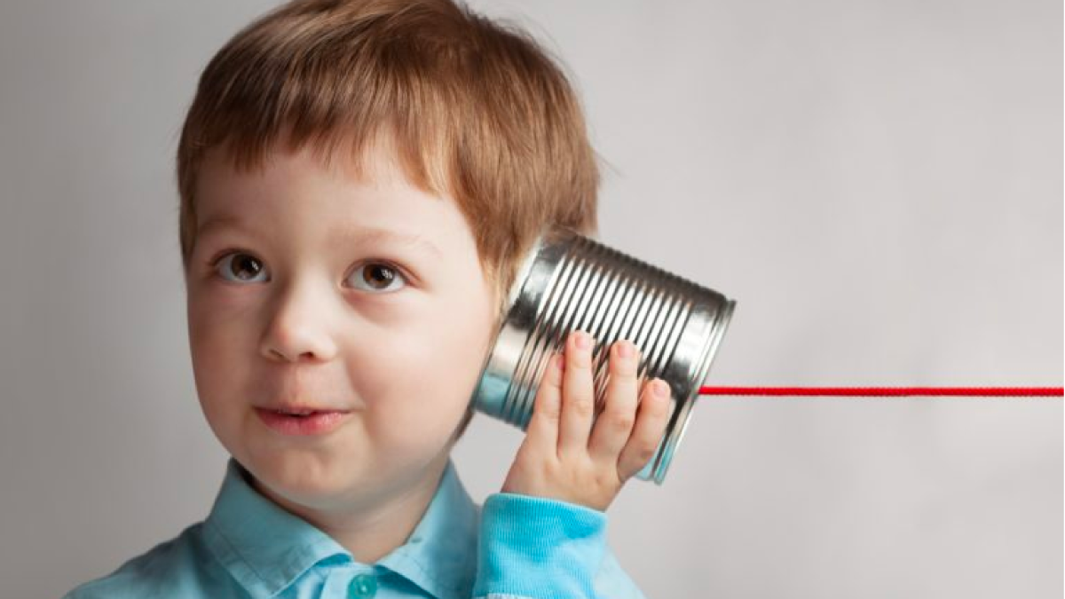 young boy listening to tin can phone