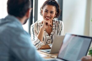 coworkers in discussion with laptops in office space