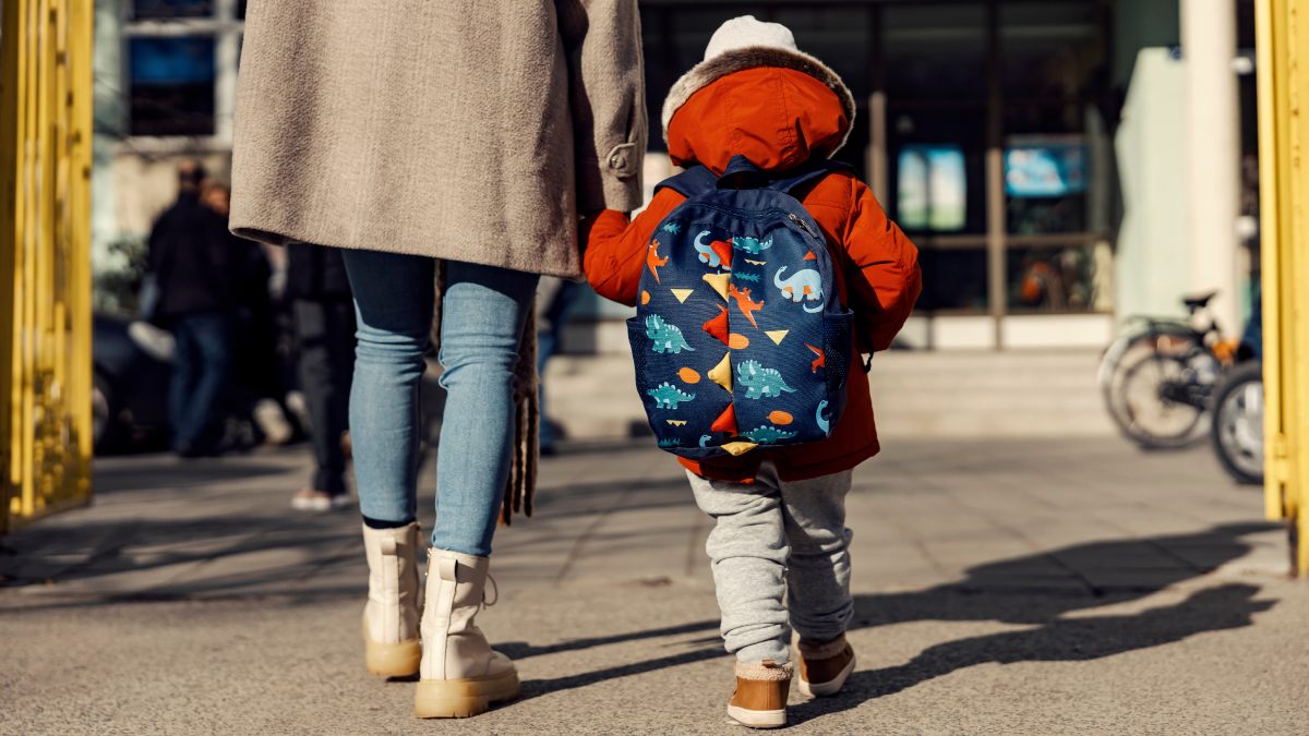 child and parent walking hand in hand to school