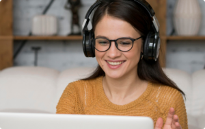 woman wearing headphones smiling while looking at a laptop screen