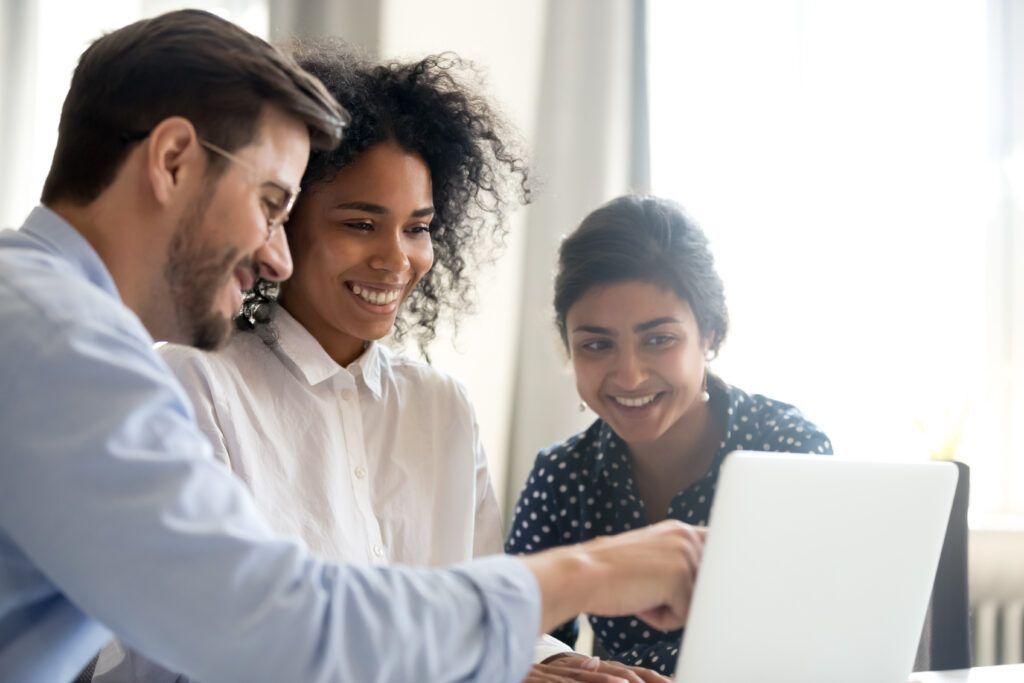 happy group of three people looking at a computer screen