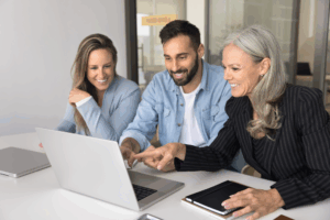 group of professionals looking at laptop screen and smiling