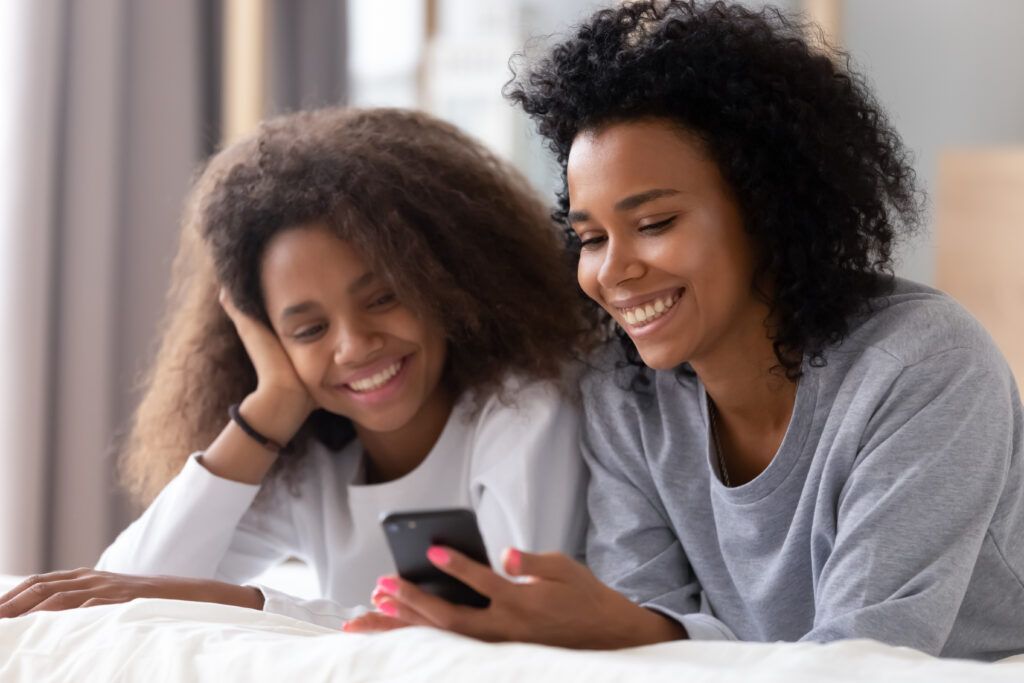 Happy mother and teen looking at phone