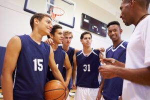 high school basketball team talking with coach on the court
