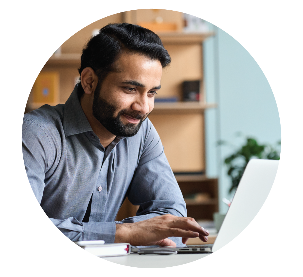 man smiling while working on laptop in office