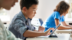 middle school student typing on tablet at classroom desk