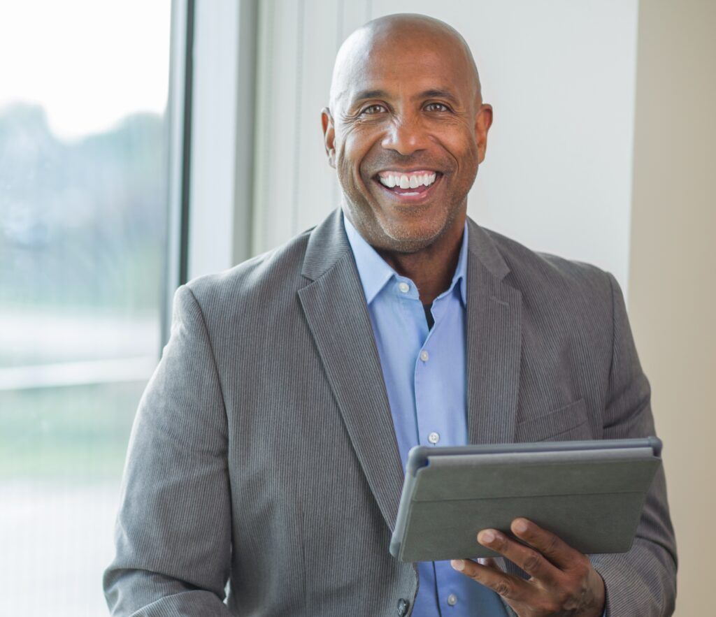 portrait of smiling African American administrator in hallway holding tablet