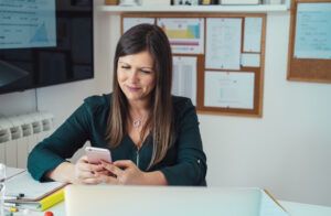 smiling teacher looking at phone in classroom