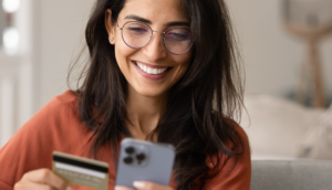 smiling woman at home making payment on her phone