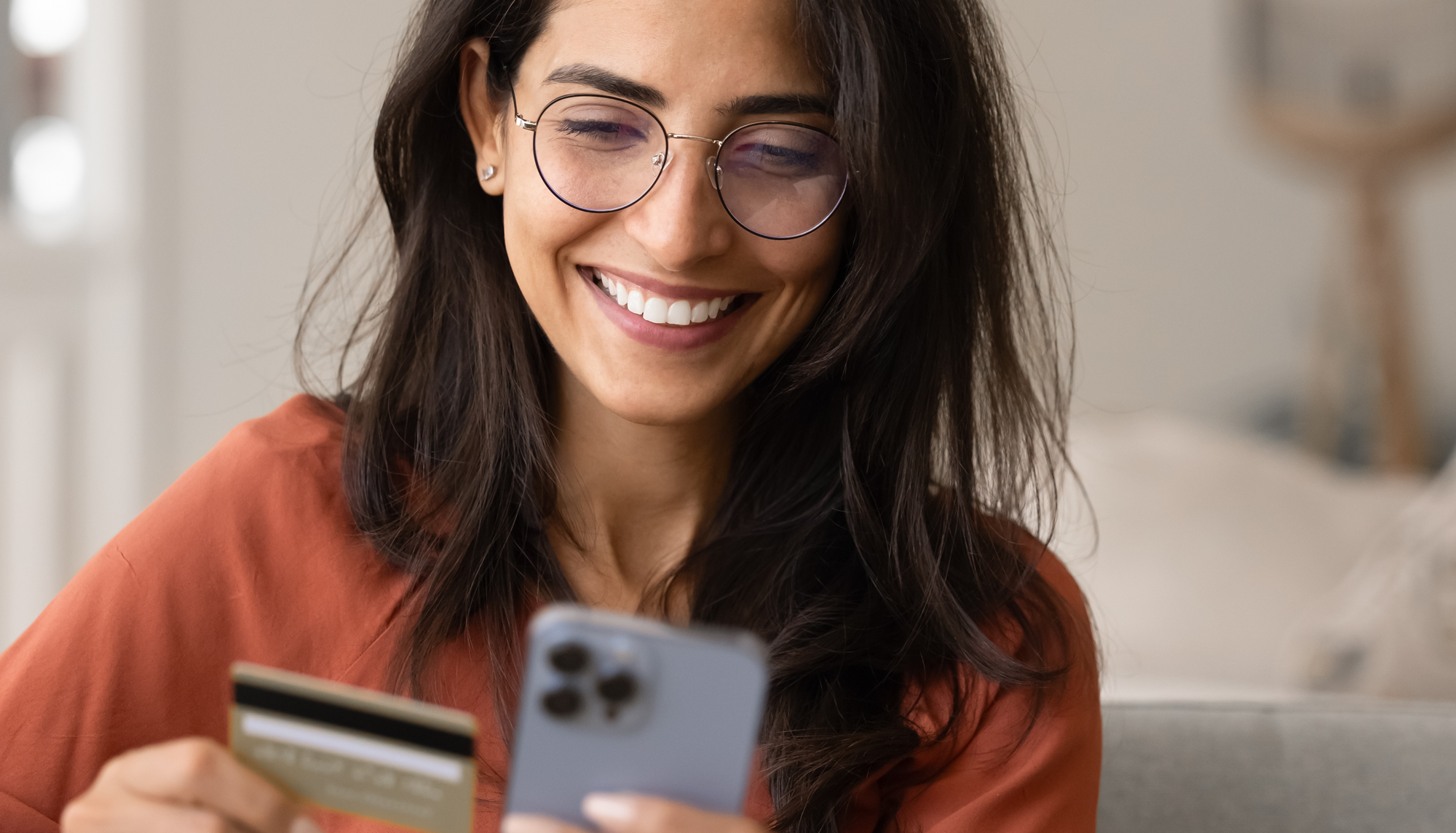 smiling woman at home making payment on her phone