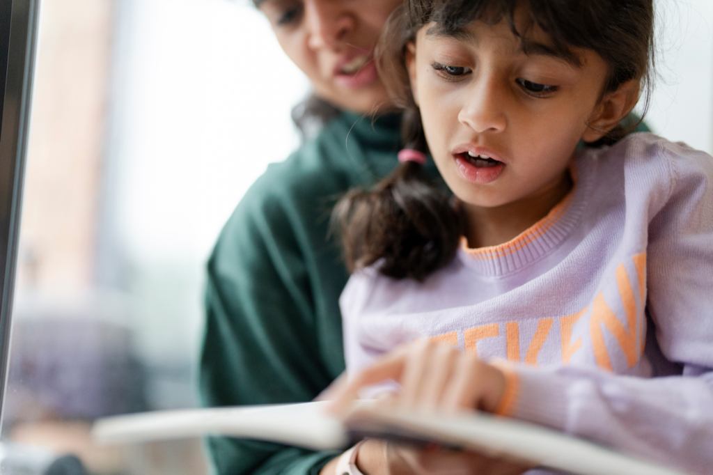 young girl reading book out loud to father