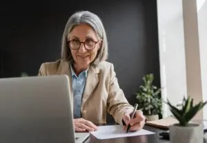 female professional taking notes while looking at laptop
