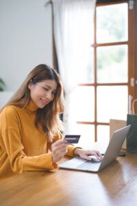 happy woman using laptop and credit card for online payment
