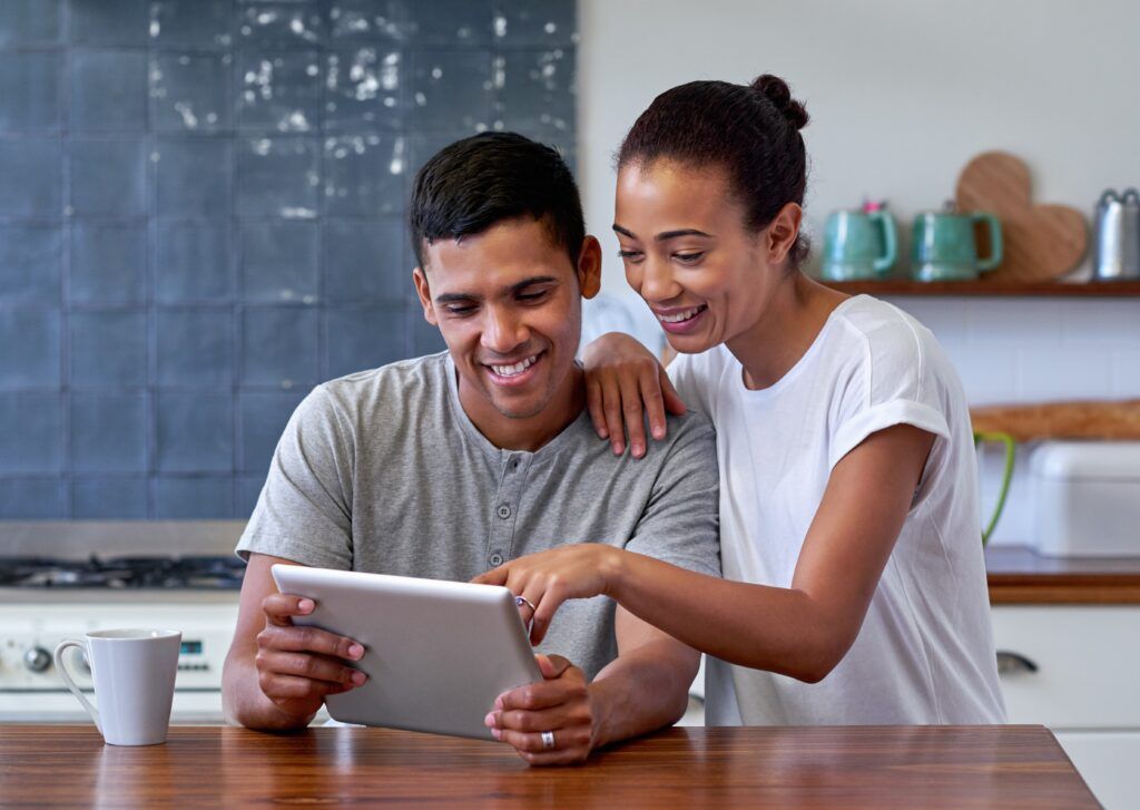 couple having morning coffee in the kitchen while looking at tablet