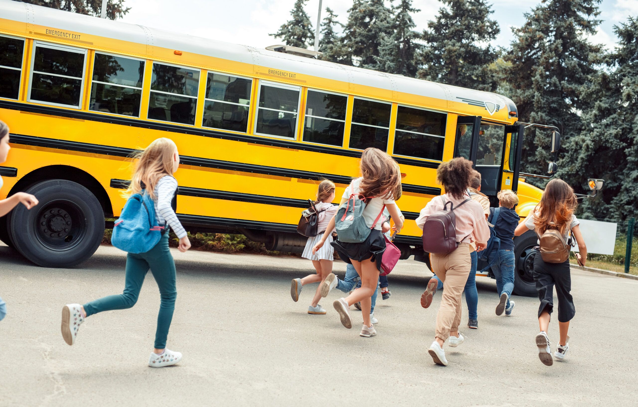 Group of children classmates runing to school bus back view