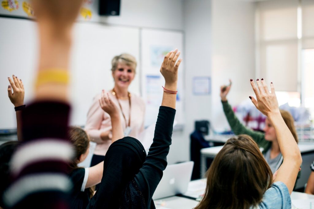 Students with their hands up responding to their teacher