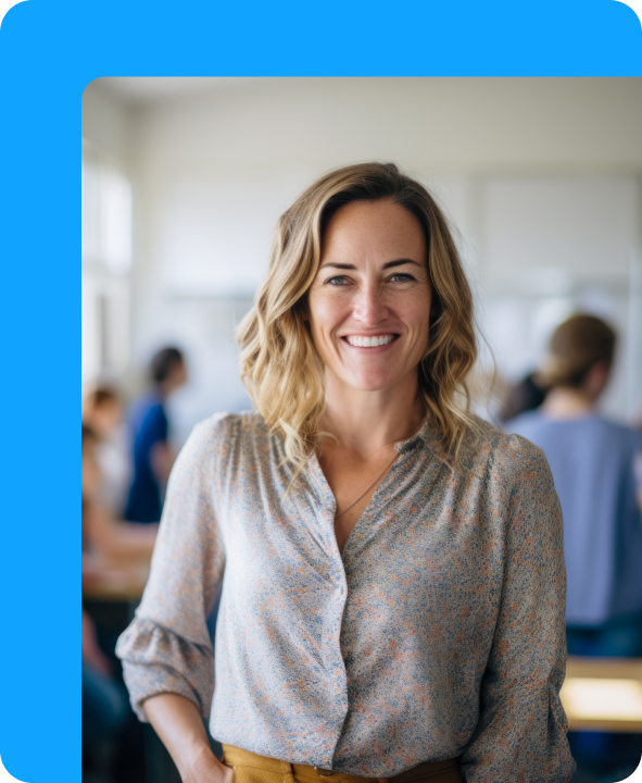Smiling school staff member standing in a bright classroom with students and colleagues in the background.