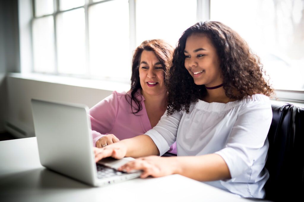 A Mother And Teenage Daughter Looking At Laptop Together