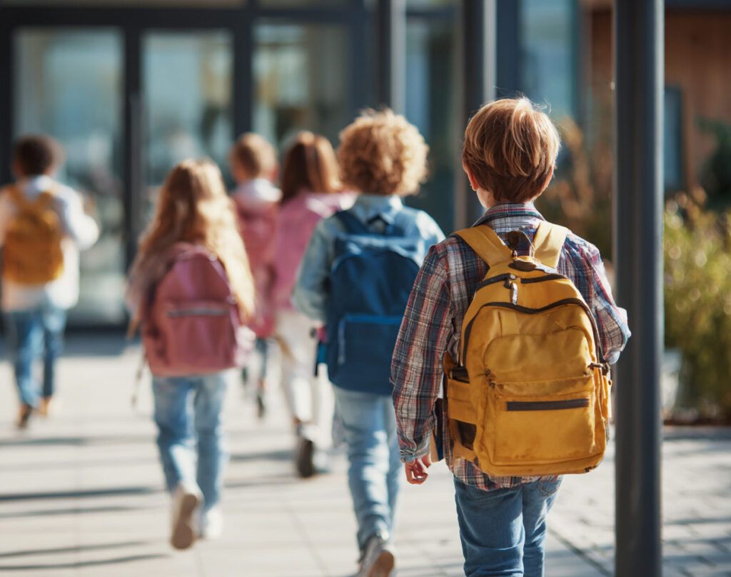 Happy students walking into school on sunny morning.