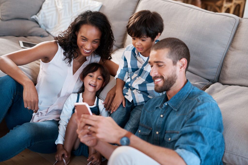 Family of four on a couch reading parent communication from their school on a cell phone