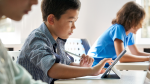 middle school student typing on tablet at classroom desk
