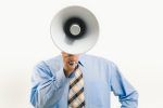 man in business attire talking into megaphone